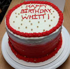 Beautiful Decorated Red Velvet Cheesecake Cake with red and white cream cheese frosting and gold pearls.