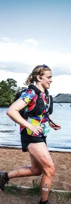 female runner running alongside a lake