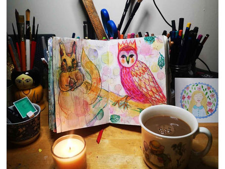 A sketch book on an art desk with coffee