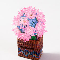 An abstract sculpture of a pot of flowers, made from blue, green, yellow and pink beads.