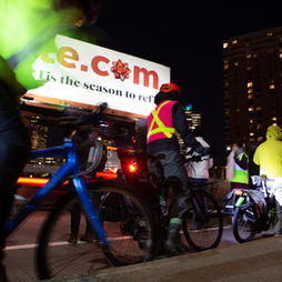 Close-up neon-clad bikers in motion against city lights and billboards.