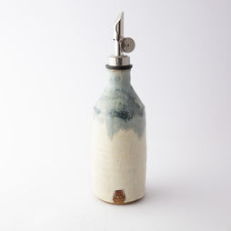 A hand-pottered bottle in a gradient of white to light blue, with a metal spigot.