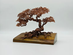 A bonsai tree made of twisted metal wire on a wood block base.