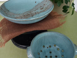 A light blue pottery bowl and colander, surrounded by everyday home decor.