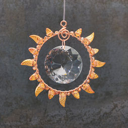 A jeweled copper suncatcher in the shape of the sun, with transparent orange leaves as rays.