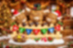 Three festive Highland cow figurines in Santa and top hats leaning over a wooden fence with a colorful “WELCOME” banner.