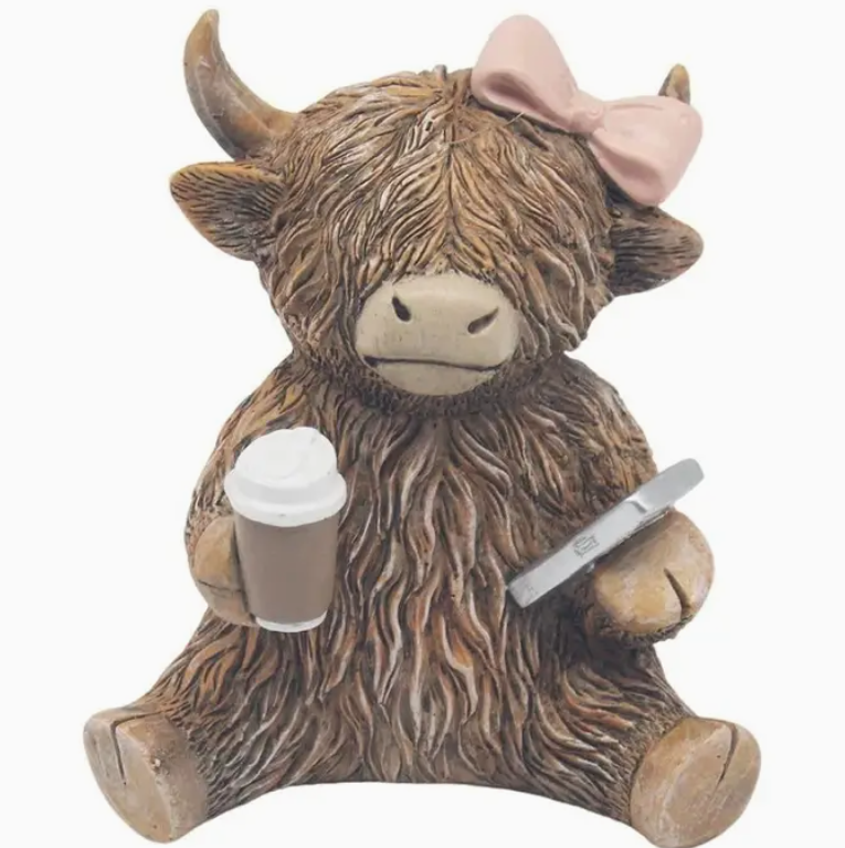 Shaggy highland cow figurine with a pink bow, holding a coffee cup and a smartphone in its hooves.