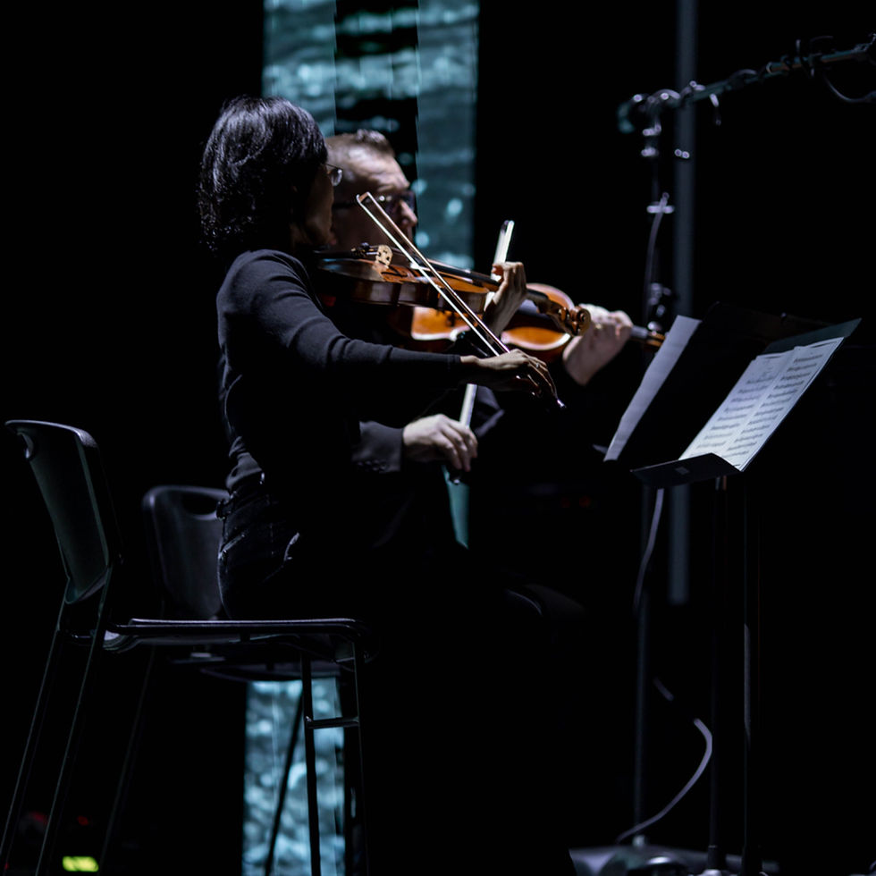 String quartet violinist performing during a Good Friday service at Manna Church in Fayetteville, North Carolina with dramatic sanctuary lighting and live sacred classical music.