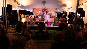 An image of Emma on stage doing comedy at a festival