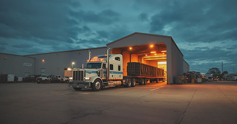semis in a steel fab shop location loading heavy loads in the dusk.jpg