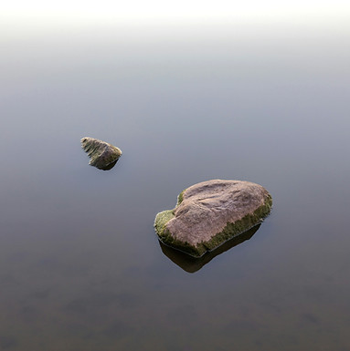 Steine im stillen Wasser als Symbol für Übergänge und neue Ausrichtung