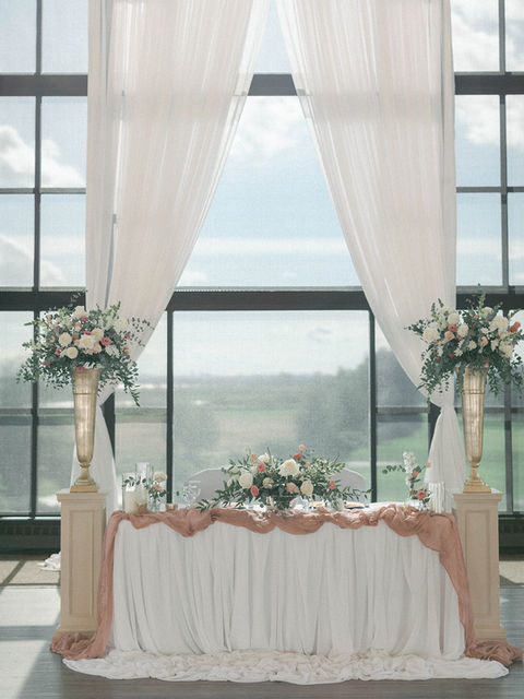 Three large floral arrangements in front of a window.