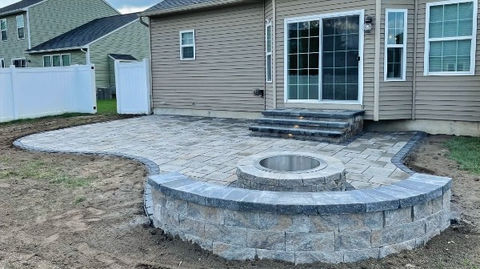 hardscaped backyard paver patio with paver stone steps and fireplace