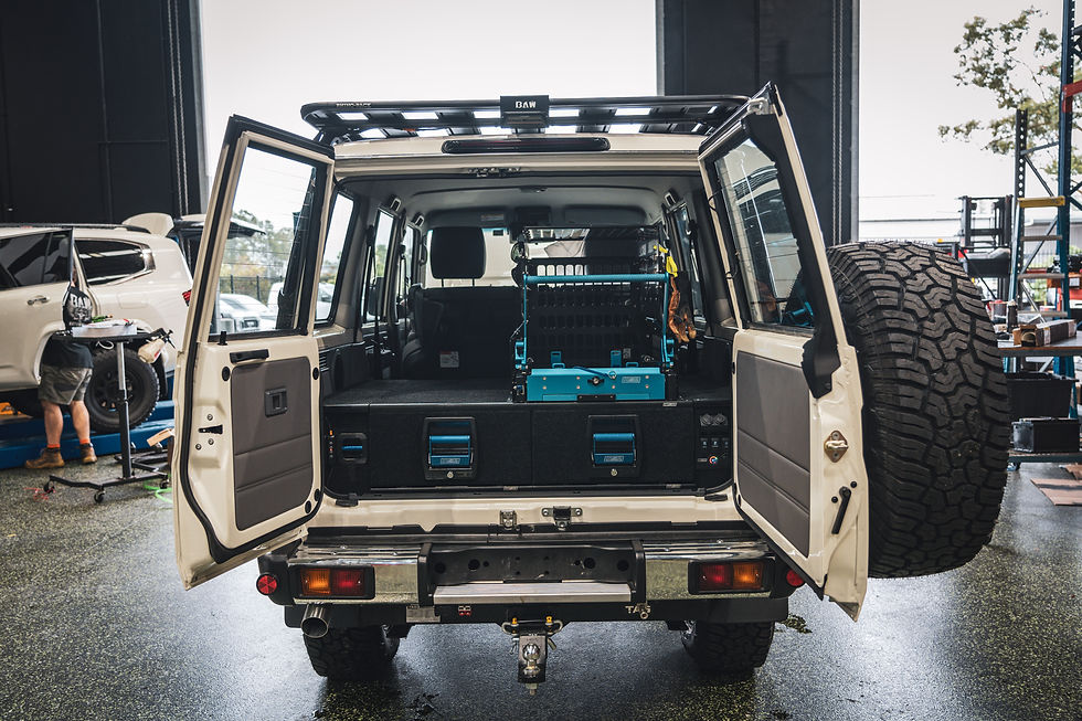 Rear view of the 76 Series with both back doors open, showing a basic drawer system and fridge slide installed.