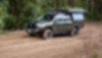 Chopped Nori Green 200 Series LandCruiser driving along a sandy track in a national park with canopy and touring gear.