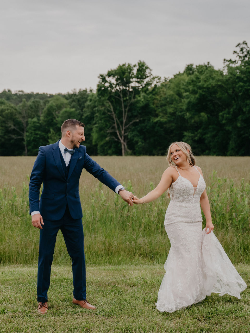 Smiling wedding couple holding hands in a field