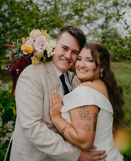 Smiling newlyweds embracing, holding a bouquet