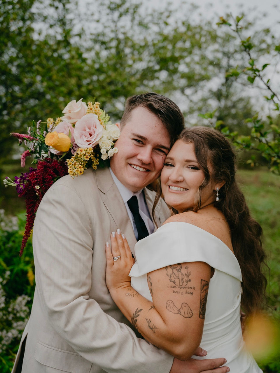 Smiling wedding couple embracing with floral bouquet