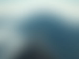 Hikers in red and tan jackets gather on a snowy mountain peak, examining a device. A yellow tent and gear are visible. Clear, sunny sky.