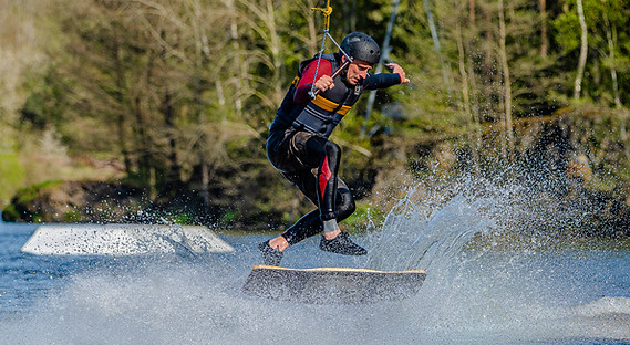 Wakeboardista ve skoku nad vodní hladinou, zachycený v dynamickém okamžiku.