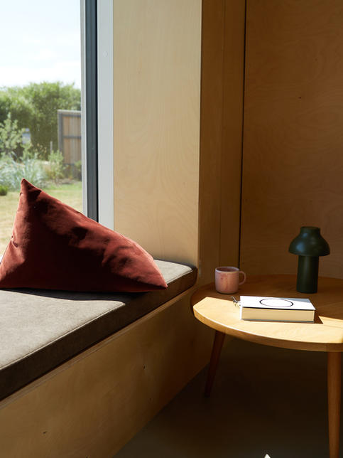 FÚ TRI cushion velluto in rust
on sofa bench with window . Fu Kissen