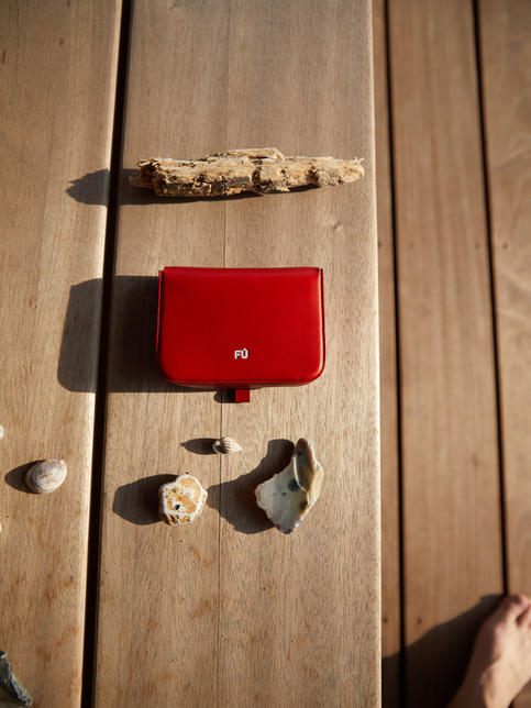 FÚ wallet on wooden bench with shells and sunshine. FÚ Geldbeutel in rot Leder. Fu Geldbeutel