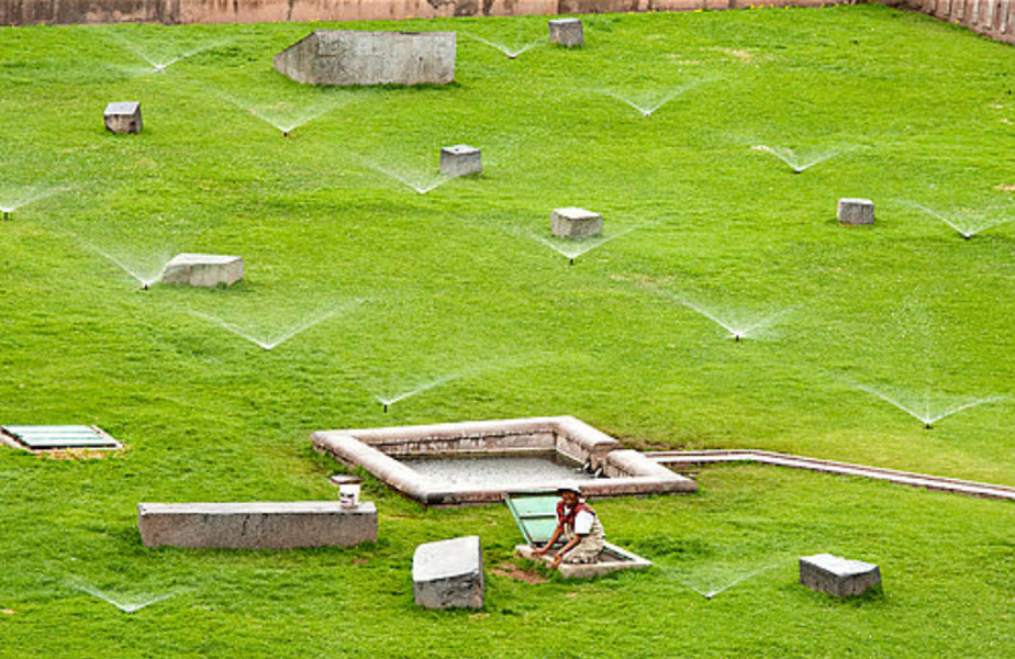 old man going down a hatch in a watered green field in peru