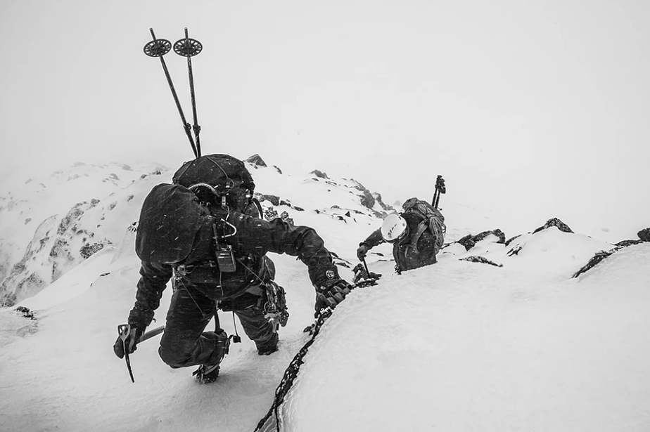 black and white photo of climbing skiers