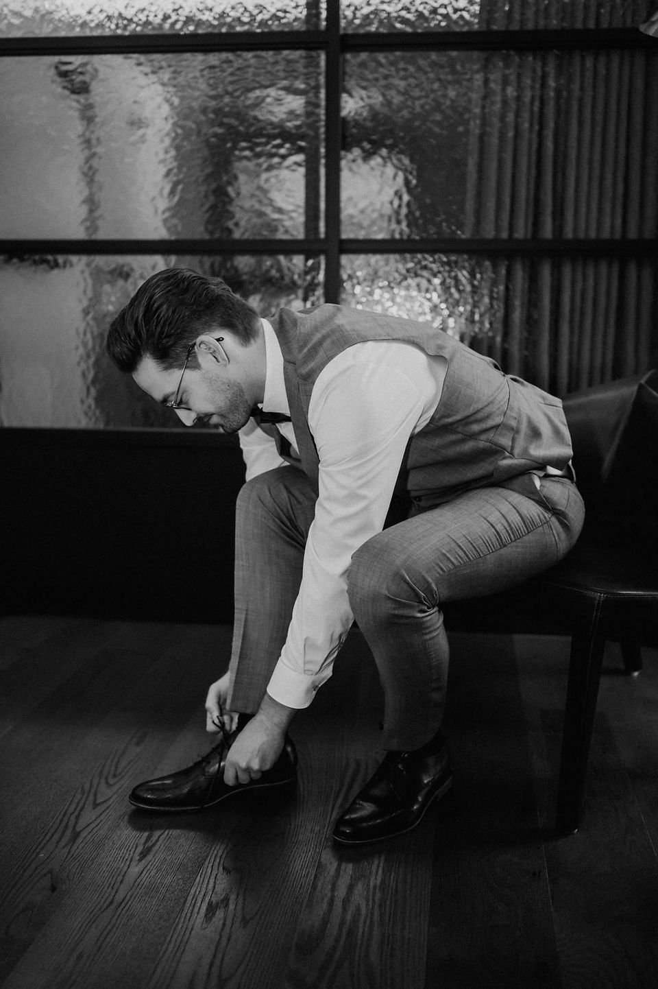 Getting Ready Bräutigam, dieser sitzt auf einem Sessel und zieht die Schuhe an