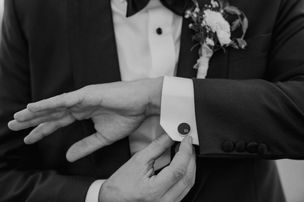 Bräutigam mit Anzug richtet personalisierten Manschettenknopf