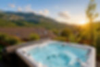 Jacuzzi extérieur dans un espace privatisé détente avec vue montagne au coucher du soleil.