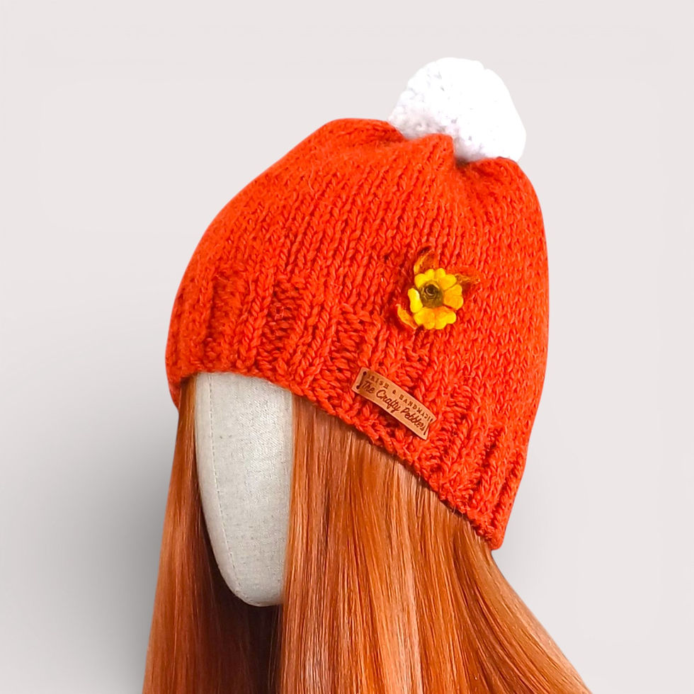 Front view of rust-coloured alpaca hat with decorative flower and pompom