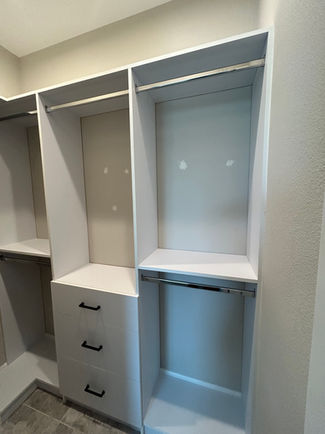 Built-in closet system with corner return shelving, angled shoe rack, and matte black drawer pulls