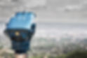 Coin-operated binoculars pointing toward a flat city.