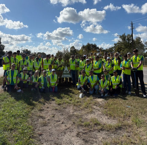 Large group of volunteers in East Houston, standing on grass.