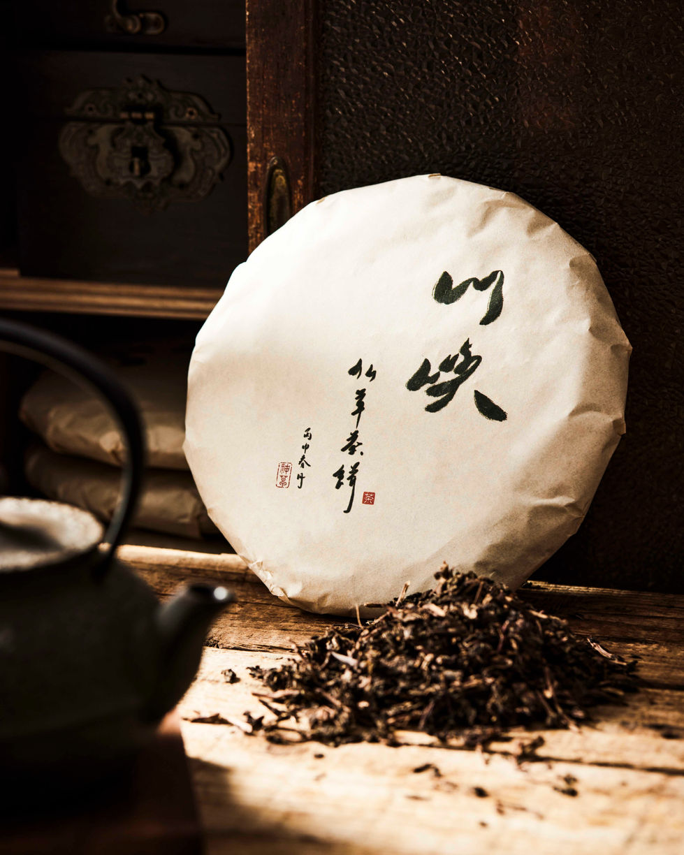 Focusing on the paper texture and calligraphy of the tea cake, complemented by warm wood tones and soft shadows to showcase t