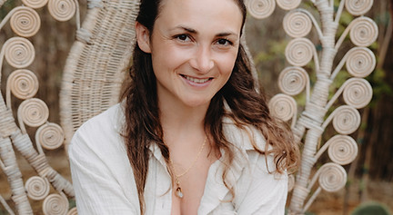 Renata sitzt auf einem Stuhl und lächelt