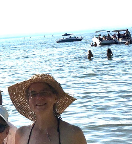 Dawn in a sun hat with boats on the water in the background