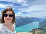 A woman with sunglasses taking a selfie in front of an Alpine lake
