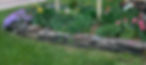 Flowers and low stone wall around Riverbend sign