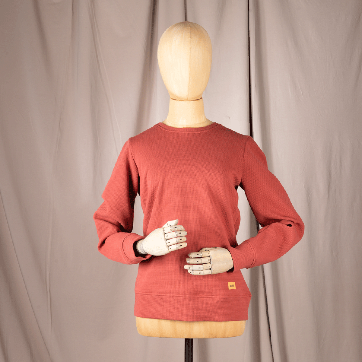 Roter Waffelstrickpullover auf Holzpuppe von vorne.