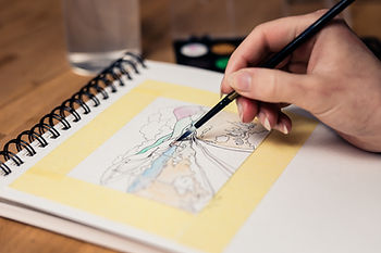 Hand malt mit Pinsel in einem Aquarell-Skizzenbuch