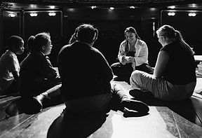 The Hero's Journey Theatre Day: Caedmon adult sitting with kids in a circle on stage