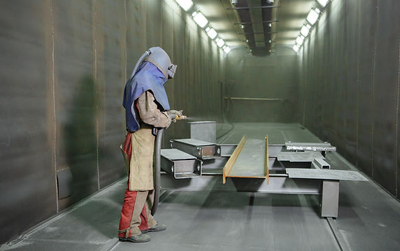 Sandblast An employee prepares a metal part for painting A harsh man works in the factory