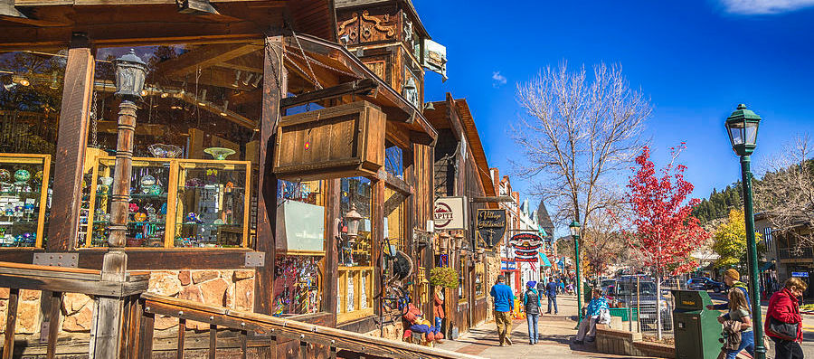 a street scene with a wooden building, people walking, and a lamppost