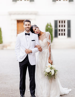 A bride and groom posing on their wedding day, lady is holding bridal flowers