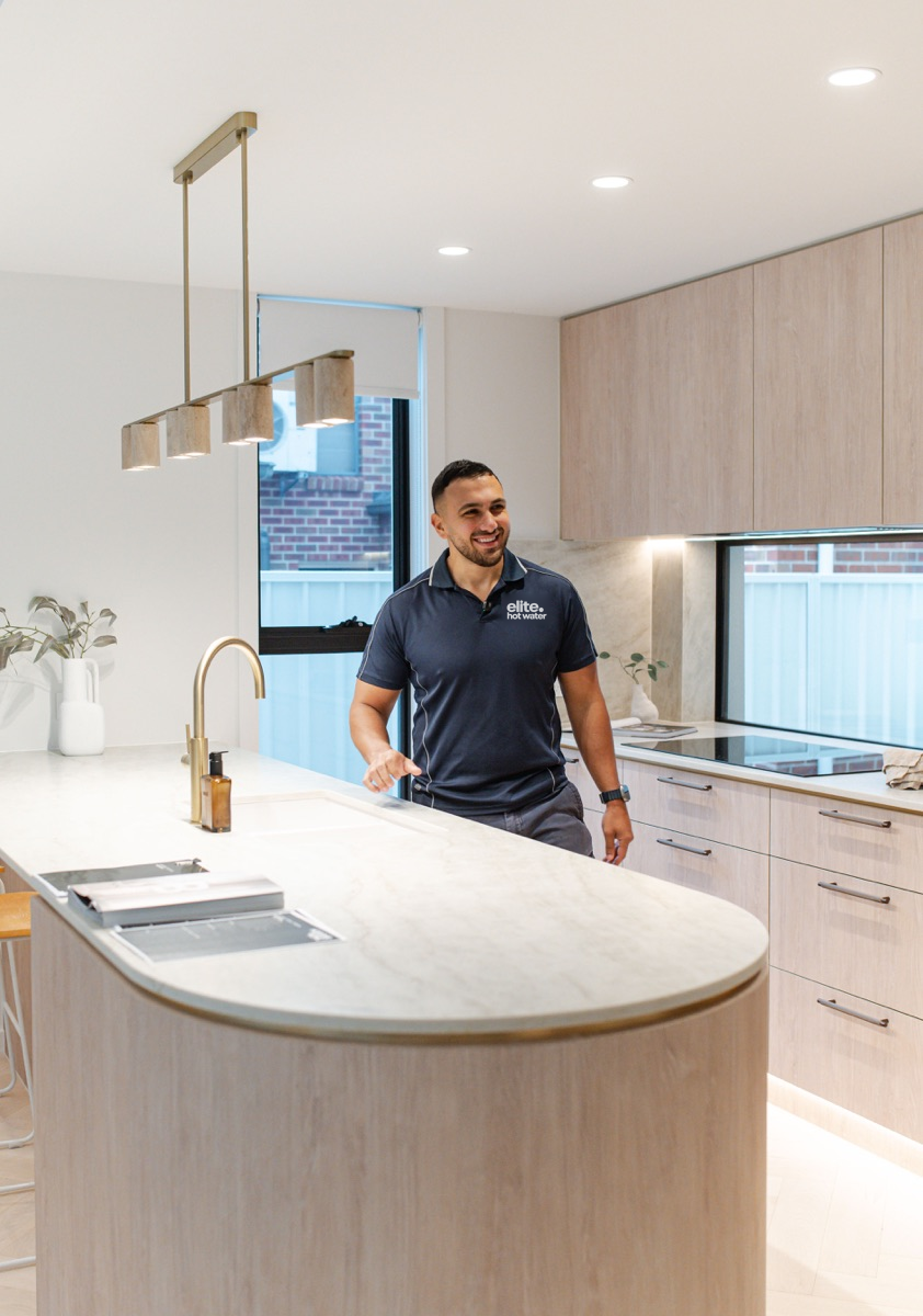 Elite plumber beside a kitchen sink and tap
