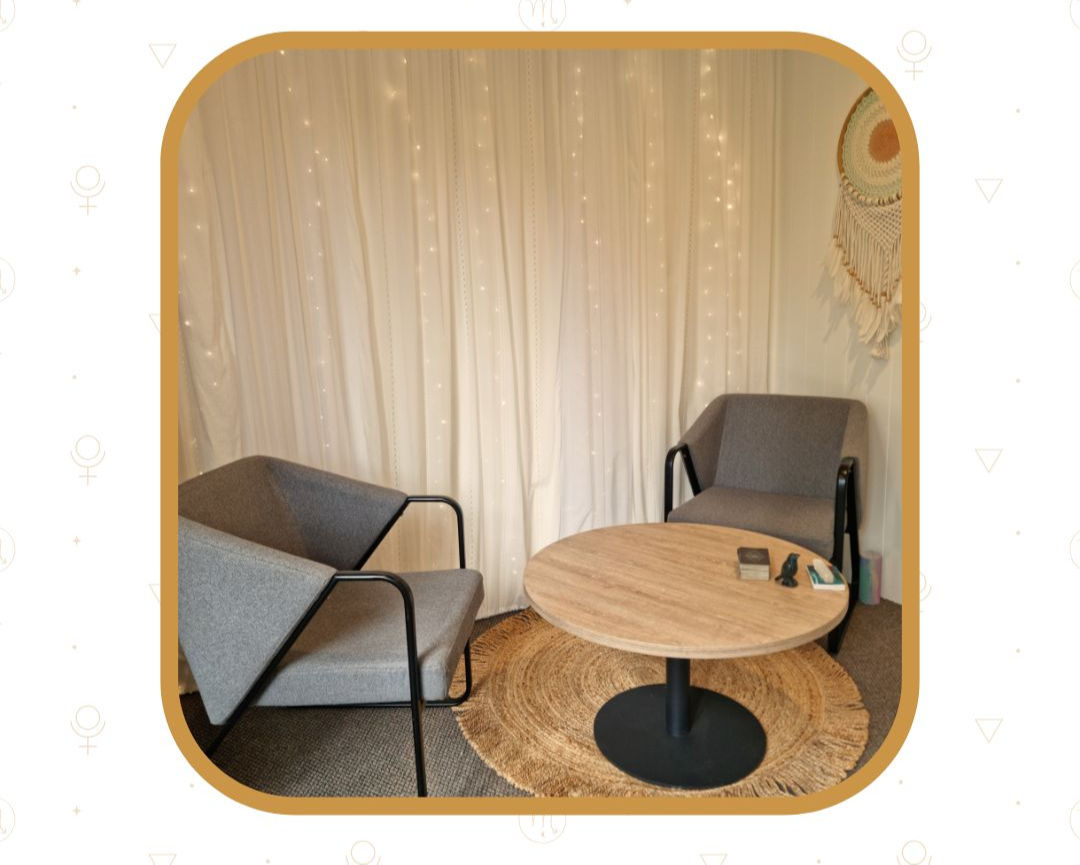 A low level round table and two grey chairs set up ready for a counselling session