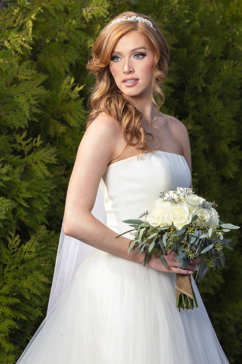 Bride in her wedding dress holding a bouquet outdoors, showcasing bridal elegance on Long Island