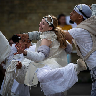 In Clouds. MCDC. Katie, Jumar and Sage dance with flying gestures in the white layered costumes and googles of the performance In Clouds.
